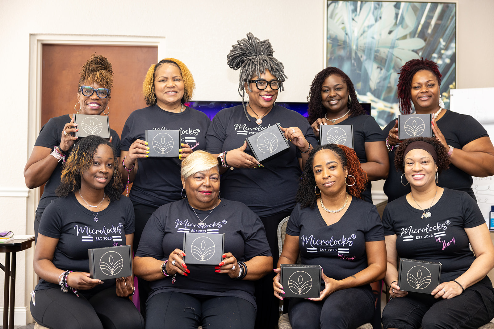 Karen and a full class of MicroLocks students holding their enrollment kits