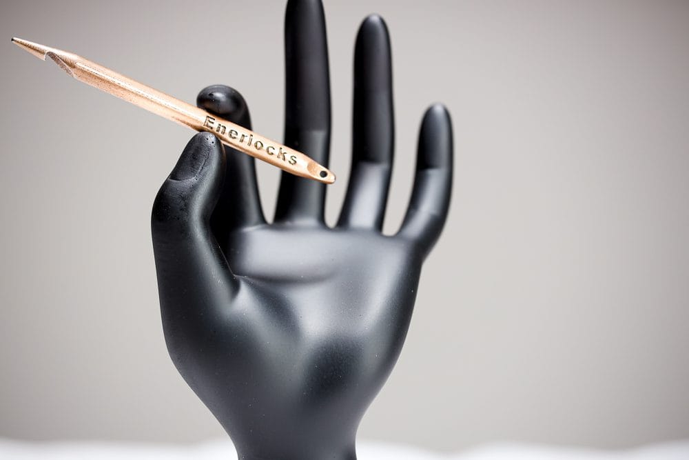 The complete gold Enerlocks locking tool displayed on a black hand form